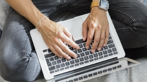 Mand sidder med sin laptop på skødet